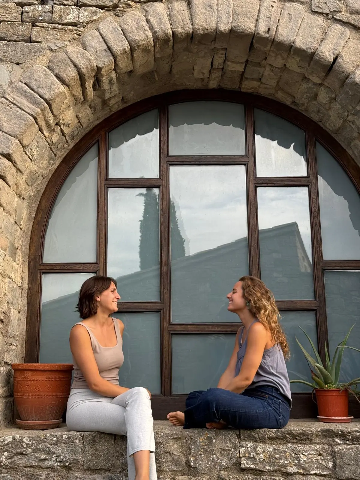 Margarita y Lucía riendo bajo el arco de la casa